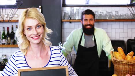 porträt von kellner und kollegen, die mit einer offenen schildtafel an der theke stehen