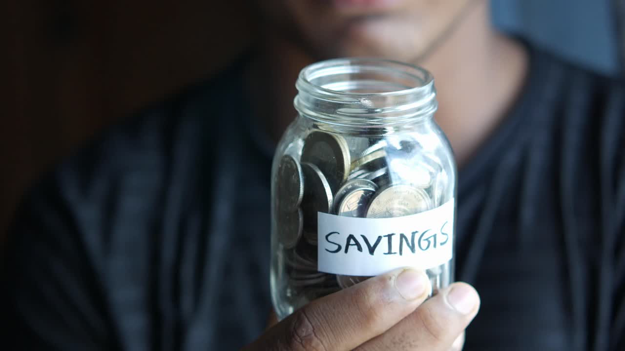 Person Holding a Saving Jar Filled with Coins