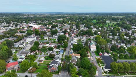 aerial view of picturesque suburban town with a patchwork of residential houses, tree lined streets, set against a backdrop of green fields and distant hills