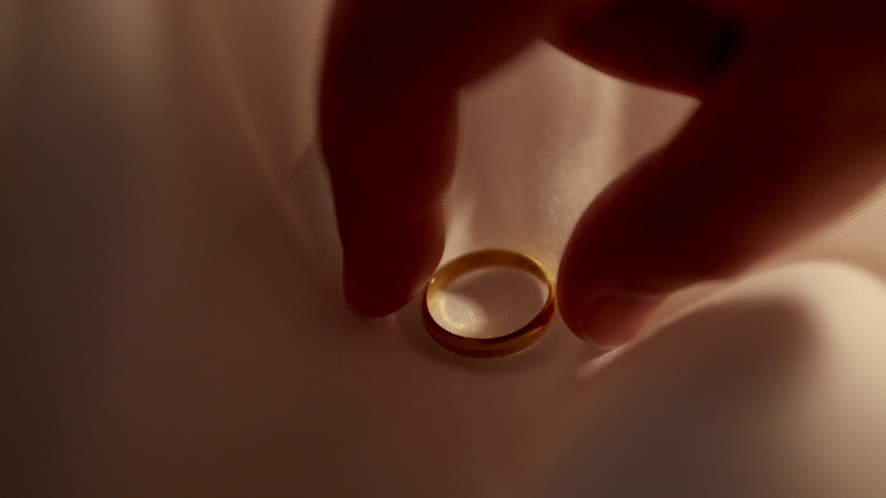 Picking up a gold ring, a precious piece of jewelry placed on a cream colored cloth