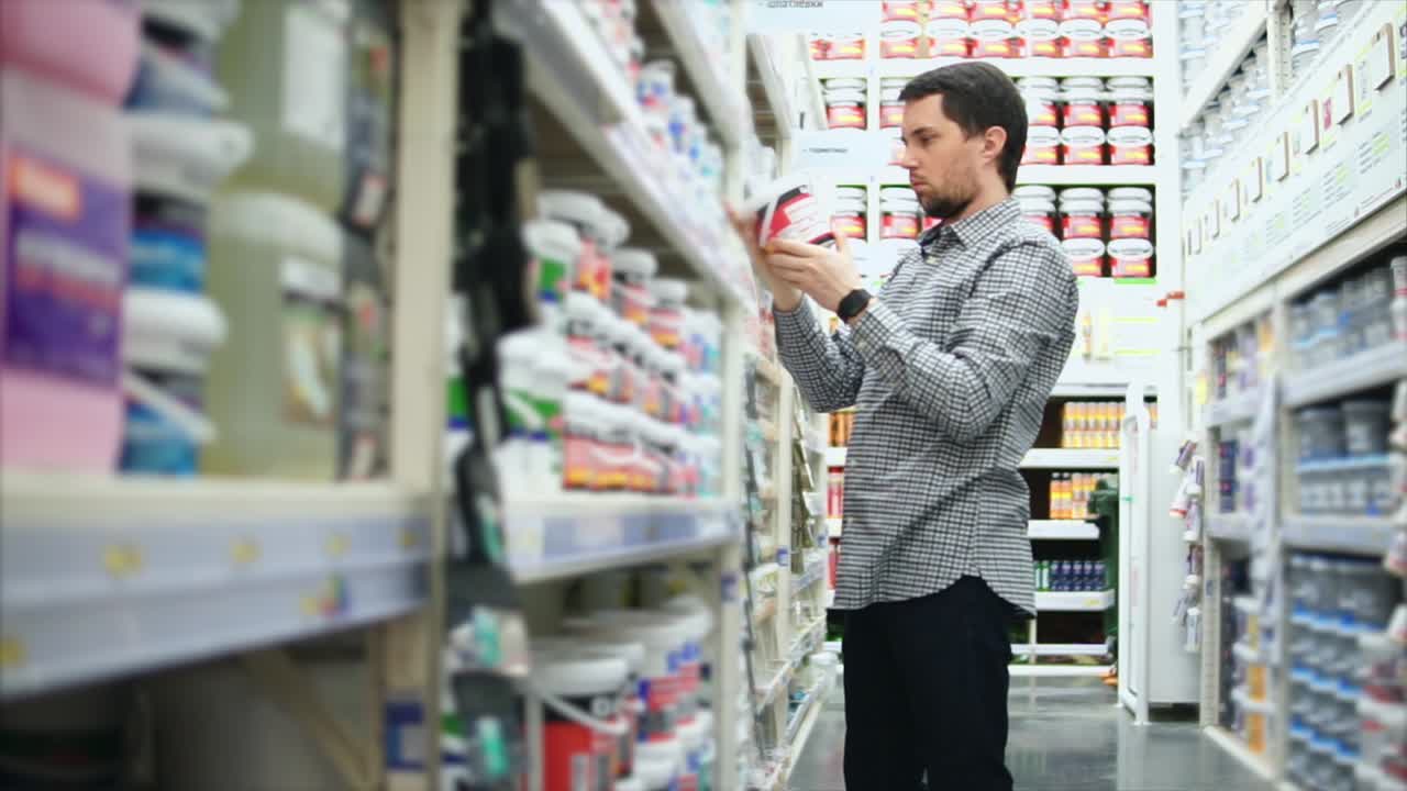hombre comprando pintura en una tienda de mejoras para el hogar