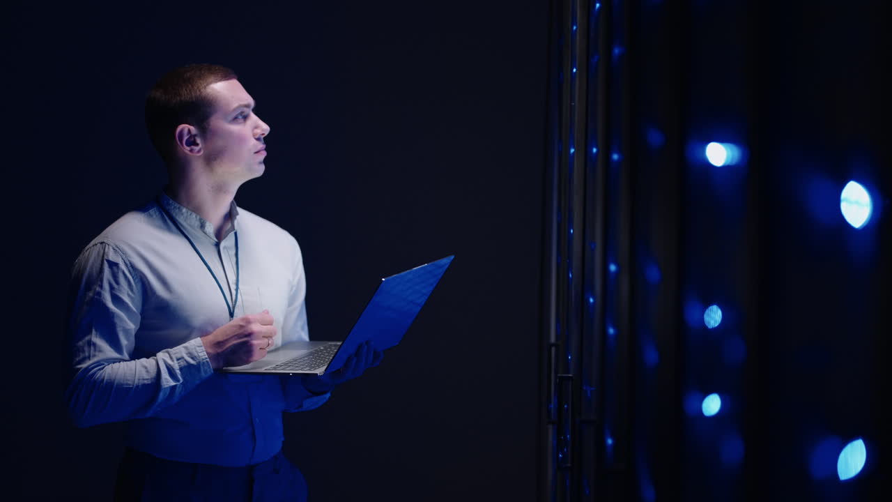 Concept of Digitalization of Information: IT Specialist In front of Server Racks with Laptop Activates Data Center with a Touch Gesture. Working on a Laptop Standing Before Open Server Rack Cabinet