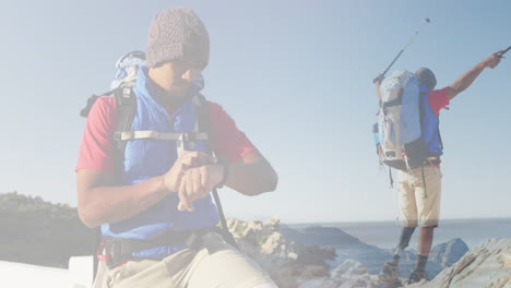 composite of happy caucasian man hiking, checking watch, and raising arms on mountainside