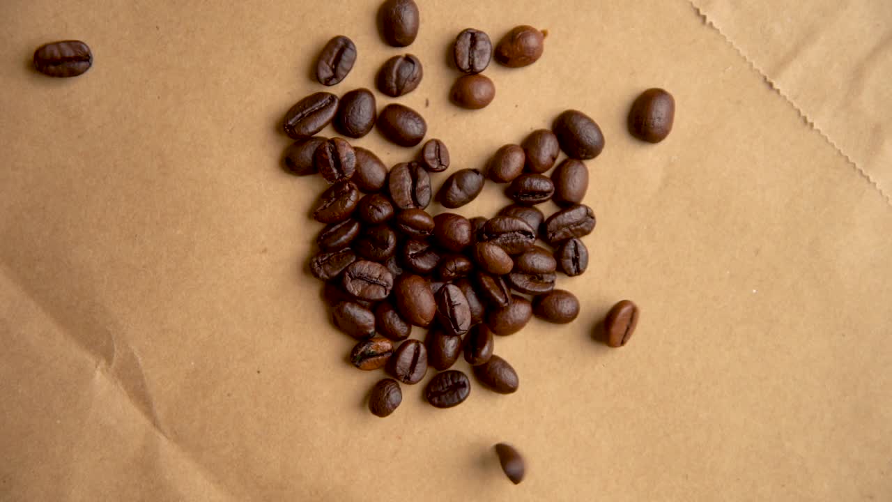 Kaffebønner falder ned fra oven på gammelt papir i slowmotion.