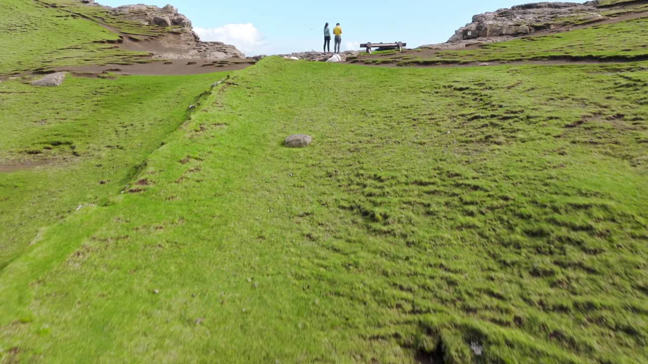 A serene green hillside in the Faroe Islands under a blue sky, peaceful and open
