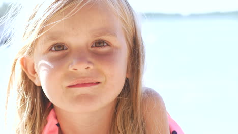 Portrait-of-kind-caucasian-girl-smiling-at-camera,-bokeh-summer-ocean-background