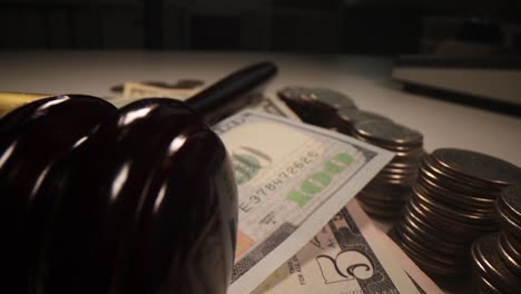 judge wooden gavel and dollar bills and coins on table closeup