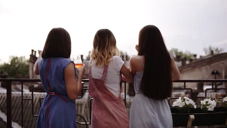 three female friends enjoying hen party on the terrace, backside view