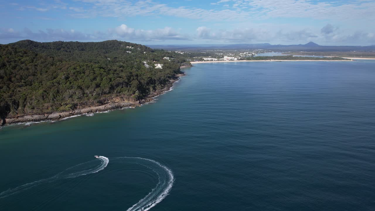 Speedboat Leaving A Wake In The Water Near A Forested Coastline In Queensland, Australia. - aerial shot