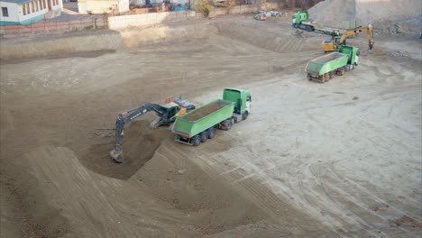 bird's-eye view of excavator digging and filling dump truck on active construction site for excavation and site preparation. preparatory work on a construction site. excavator loading dirt into truck.