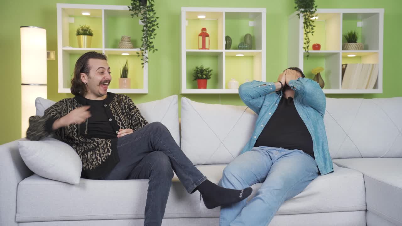 행복하고 유쾌한 남성 친구들은 집에서 즐겁고 미소 짓습니다.