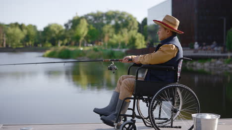 man in wheelchair fishing in a park