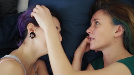 top view of two young women lying in bed, caress and stroke