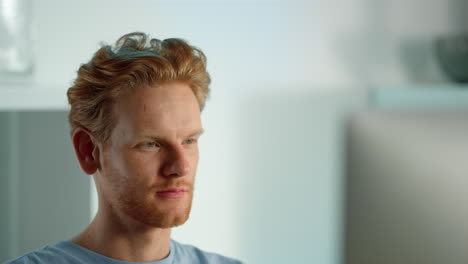 smiling man looking computer screen closeup. relaxed ginger guy watching blog