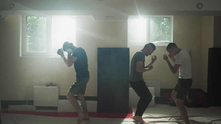 Male boxers actively engaged in boxing walking in circles during group lesson with trainer. Improved stamina and physical health in equipped room for athletes