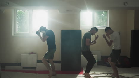 male boxers actively engaged in boxing walking in circles during group lesson with trainer. improved stamina and physical health in equipped room for athletes