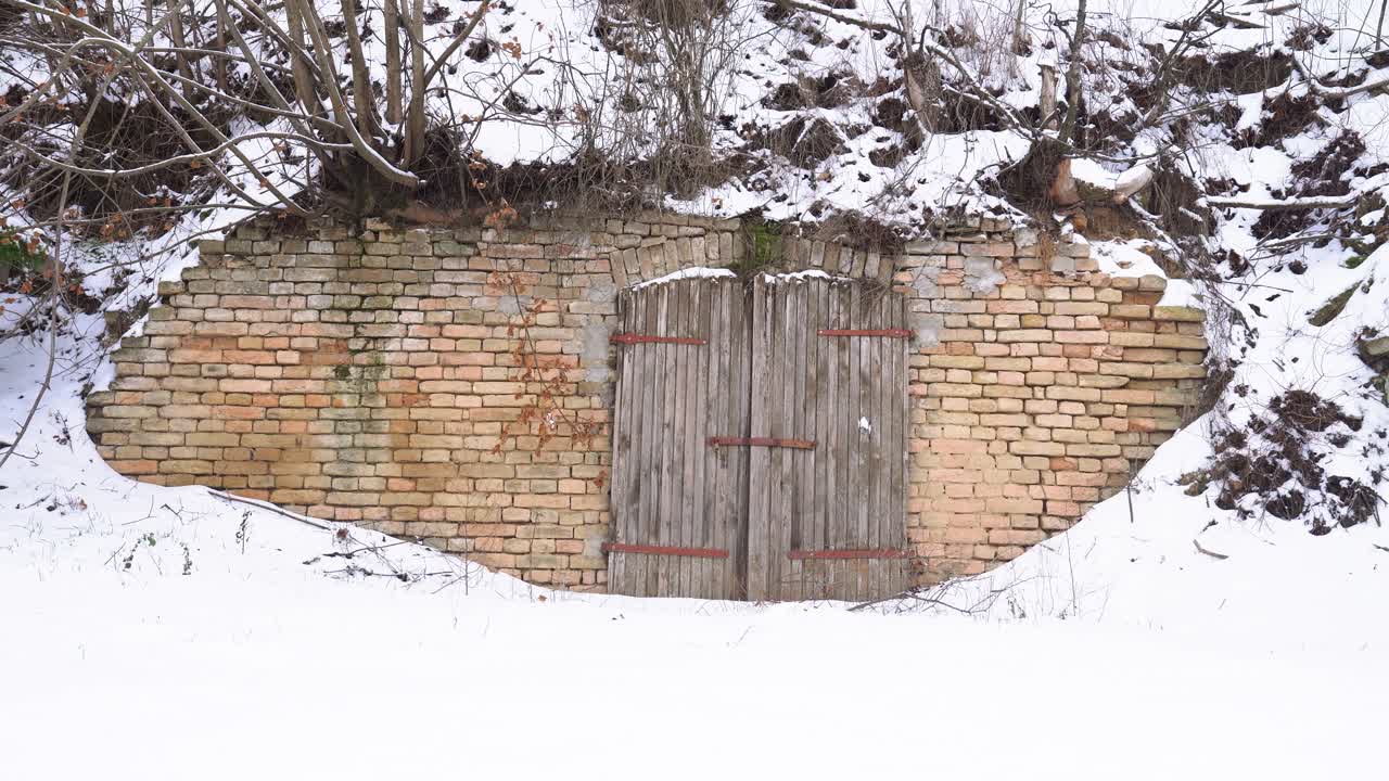 Lối vào hầm rượu gạch cũ nằm trong sườn đồi phủ tuyết ở Nemesnádudvar, Hungary.