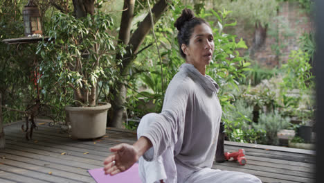 focused biracial woman practicing yoga on terrace, slow motion