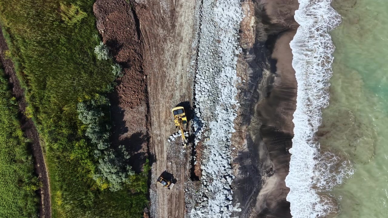 Lavori di costruzione sono in corso lungo la costa mentre gli operai migliorano il litorale in una zona costiera durante il giorno.