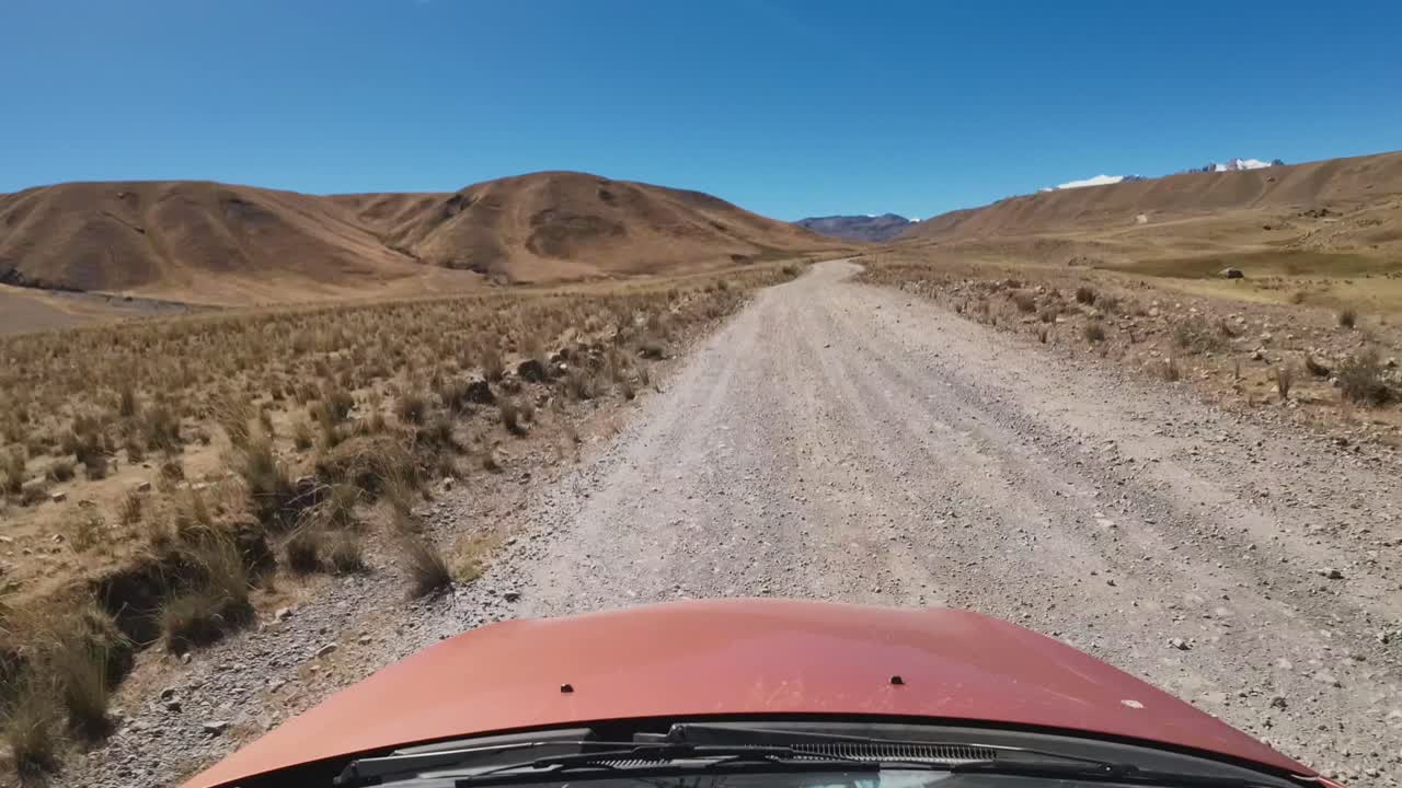 Auto che guida su una strada sterrata attraverso un paesaggio montano arido