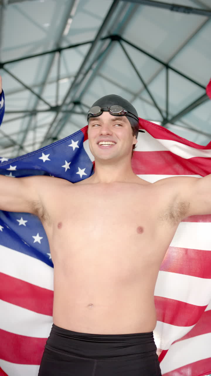 Vertical video: Holding American flag, swimmer celebrating victory at indoor pool with teammates