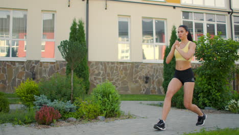 una mujer hace saltos en un sendero de la acera en un parque en un entorno urbano. disparo en cámara lenta de una mujer en ropa deportiva con un salto