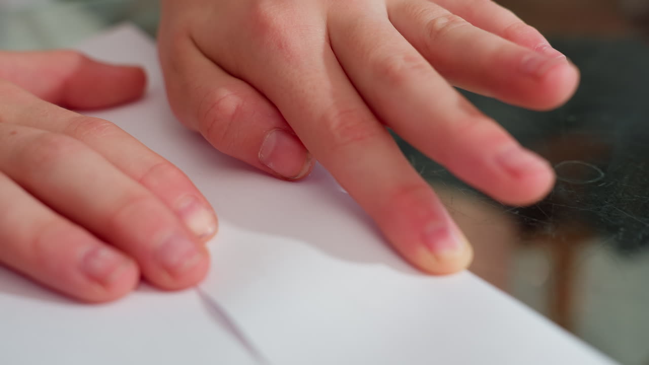 Close-up of hand folding and carefully creating paper craft on table, aligning edges with precision for a neat finish