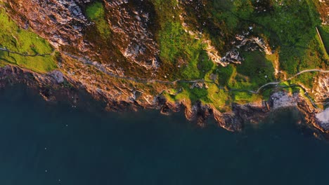 aerial view of howth’s rocky coastal cliffs and calm sea during golden sunset