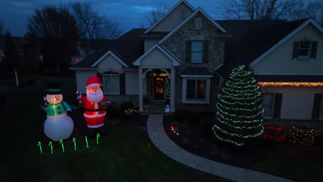 inflatable santa and frosty the snowman with christmas light decorations at two story american home during holiday season