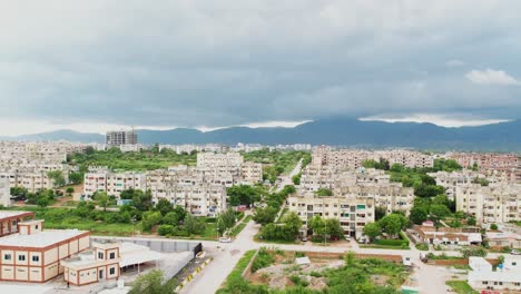 Luftaufnahmen-Von-Engen-Betongebäuden-Einer-Großstadt-Mit-Dem-Berg-Im-Hintergrund,-Der-Tagsüber-Mit-Dunklen-Wolken-Bedeckt-Ist