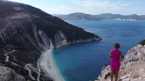 woman on the coastline watches sea and beach