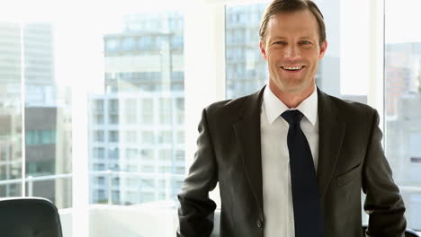 Happy-businessman-standing-by-window