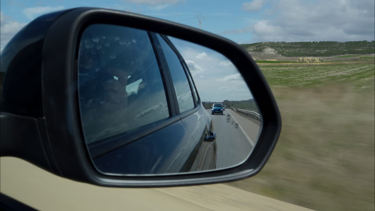 Car Side Mirror View of Road and Following Vehicle