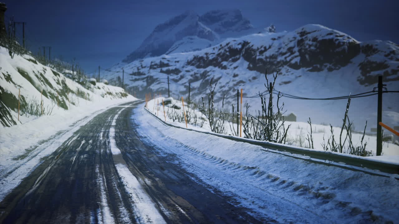 Snow covered road winding through mountain landscape during twilight