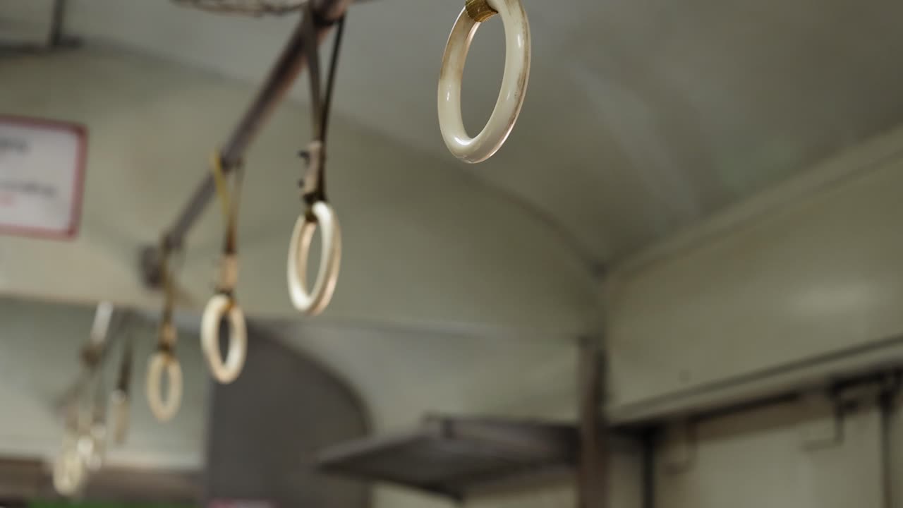 Nahaufnahme von weißen Halteringen aus Plastik, die im Inneren eines fahrenden öffentlichen Verkehrsmittels schwingen