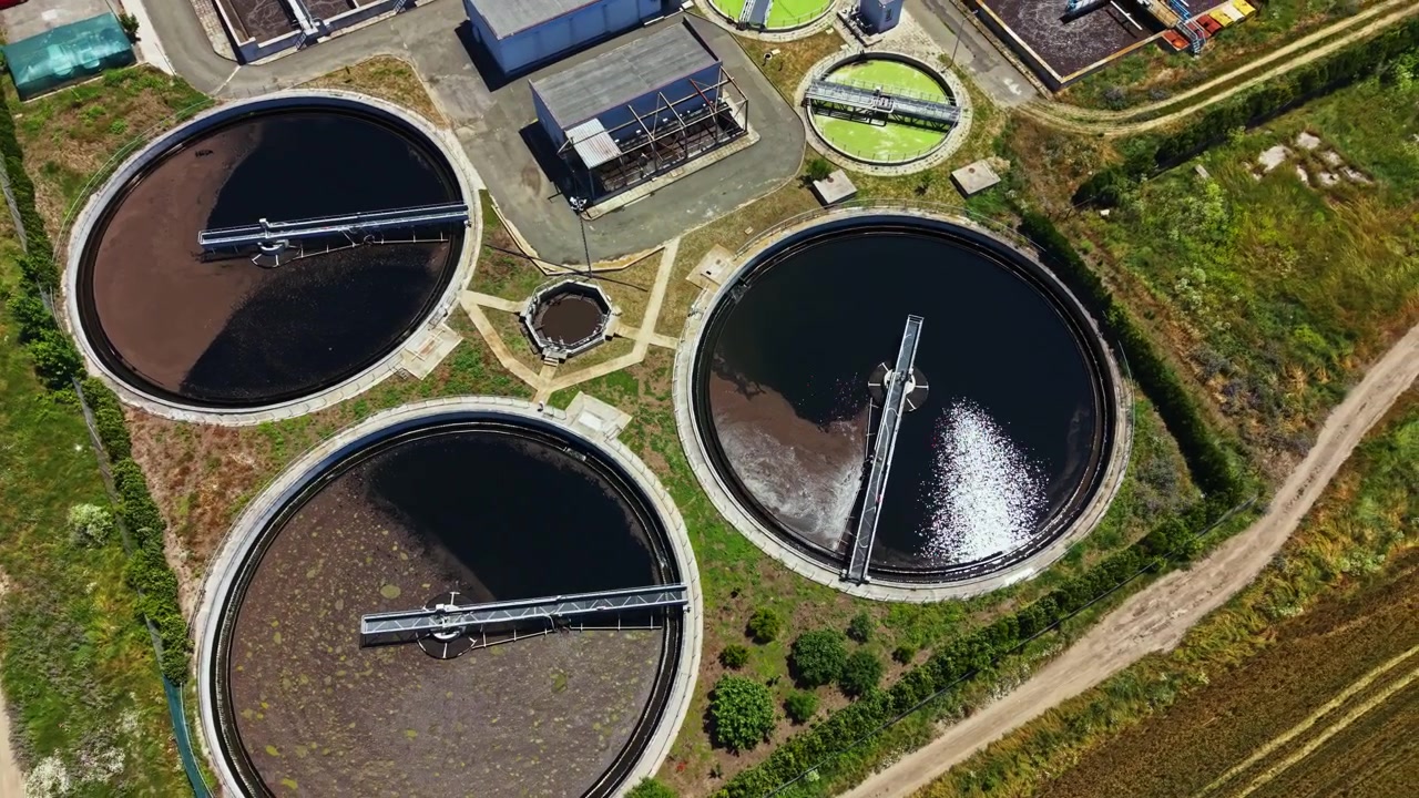 Water treatment facility in operation with multiple circular tanks for processing wastewater located in an industrial area during daytime