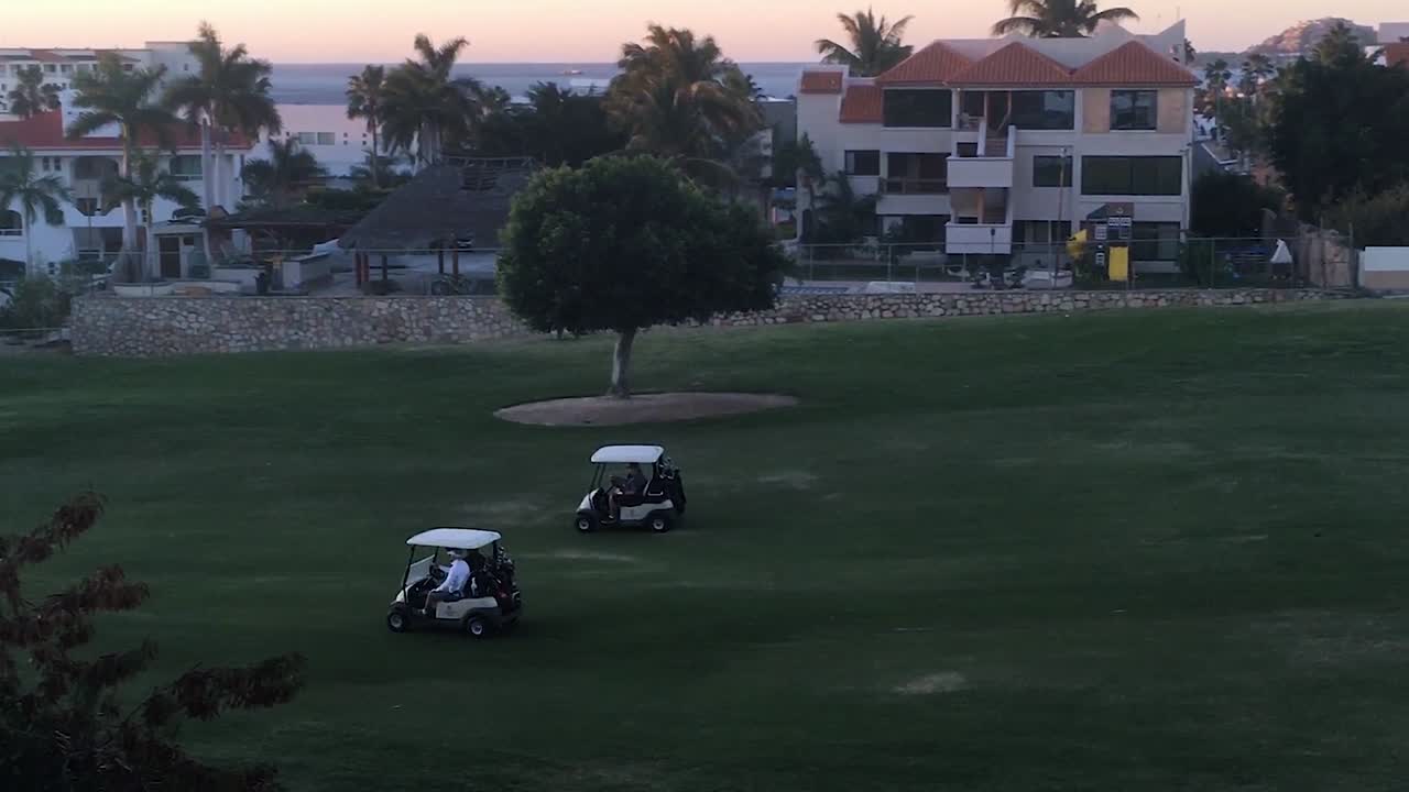 Men Driving Two Golf Carts Across a Golf Course Early in the Morning in San Jose del Cabo, Mexico