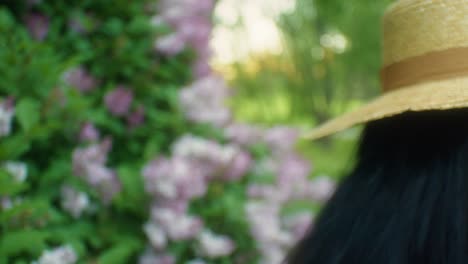 mujer negra caminando hacia flores lilas oliendo seguido