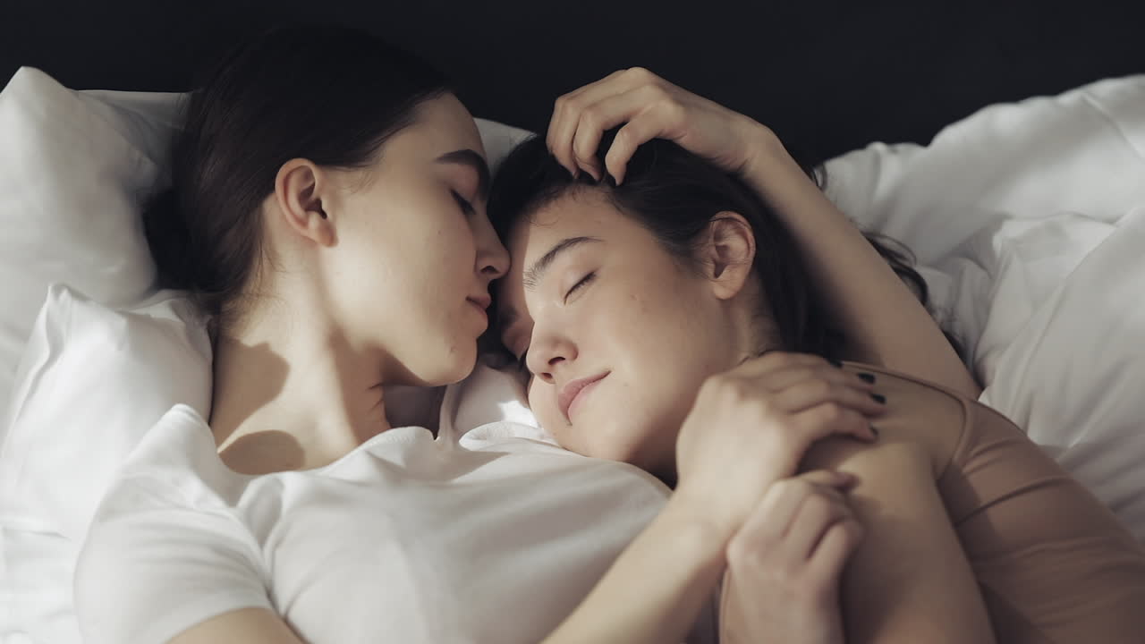 Two affectionate lesbian women cuddling in bed