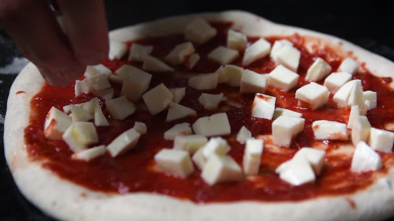 nærbillede af kokken, der laver hjemmelavet surdegpizza med salsa og mozzarella ost terninger