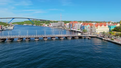 Drone-push-in-to-Queen-Emma-pontoon-bridge-in-Handelskade-Punda-District-Willemstad-Curacao-with-Juliana-bridge-behind