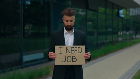 unemployed businessman holding a cardboard sign