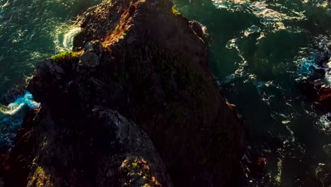 vista aérea de la puesta de sol de acantilados rocosos y olas verdes del océano en big sur california