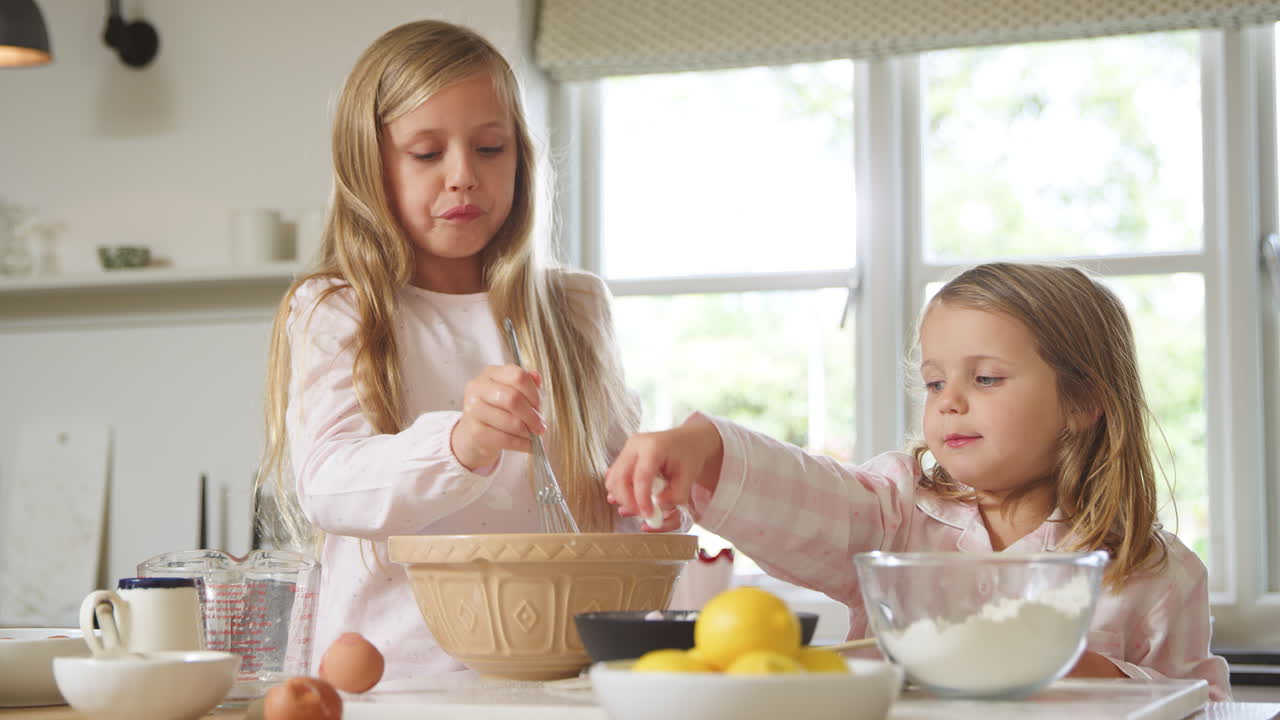 dos chicas con pijama horneando en la cocina en casa juntas