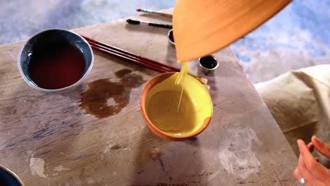 Male-potter-pouring-watercolor-in-bowl-at-pottery-workshop