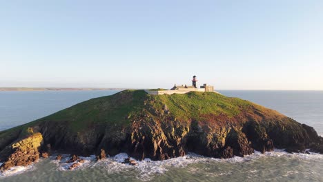 ballycotton lighthouse on a green island, surrounded by the atlantic under soft light