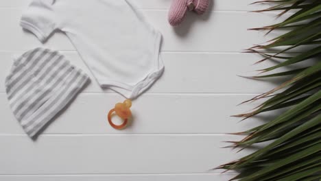 video of white baby grow, hat, dummy and pink booties with copy space on white background