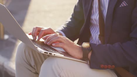 mid section of asian man using laptop wile sitting at corporate park