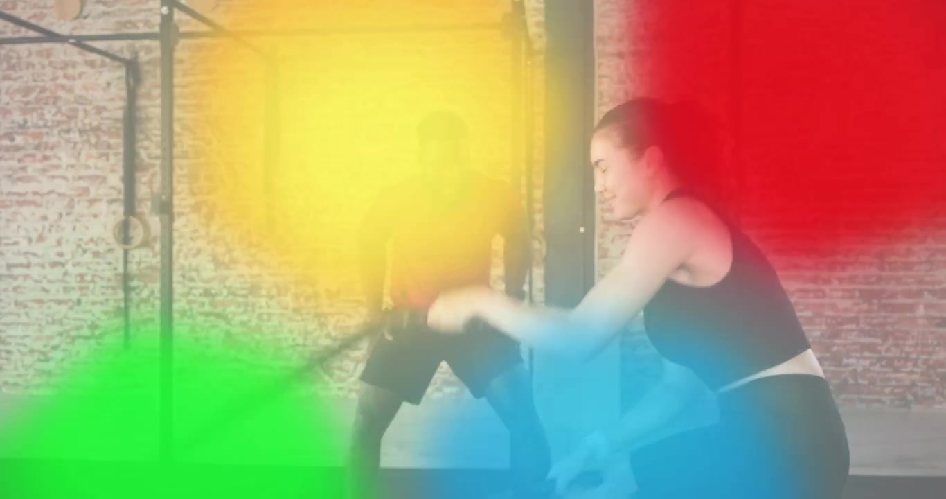 Kvinnlig tränande svingar battle ropes i gymmet, manlig tränare anger tempot och de ger varandra en high five.