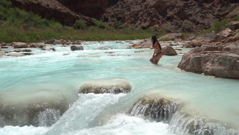 woman in bikini goin in turquoise river water, hopi salt trail, grand canyon national park usa